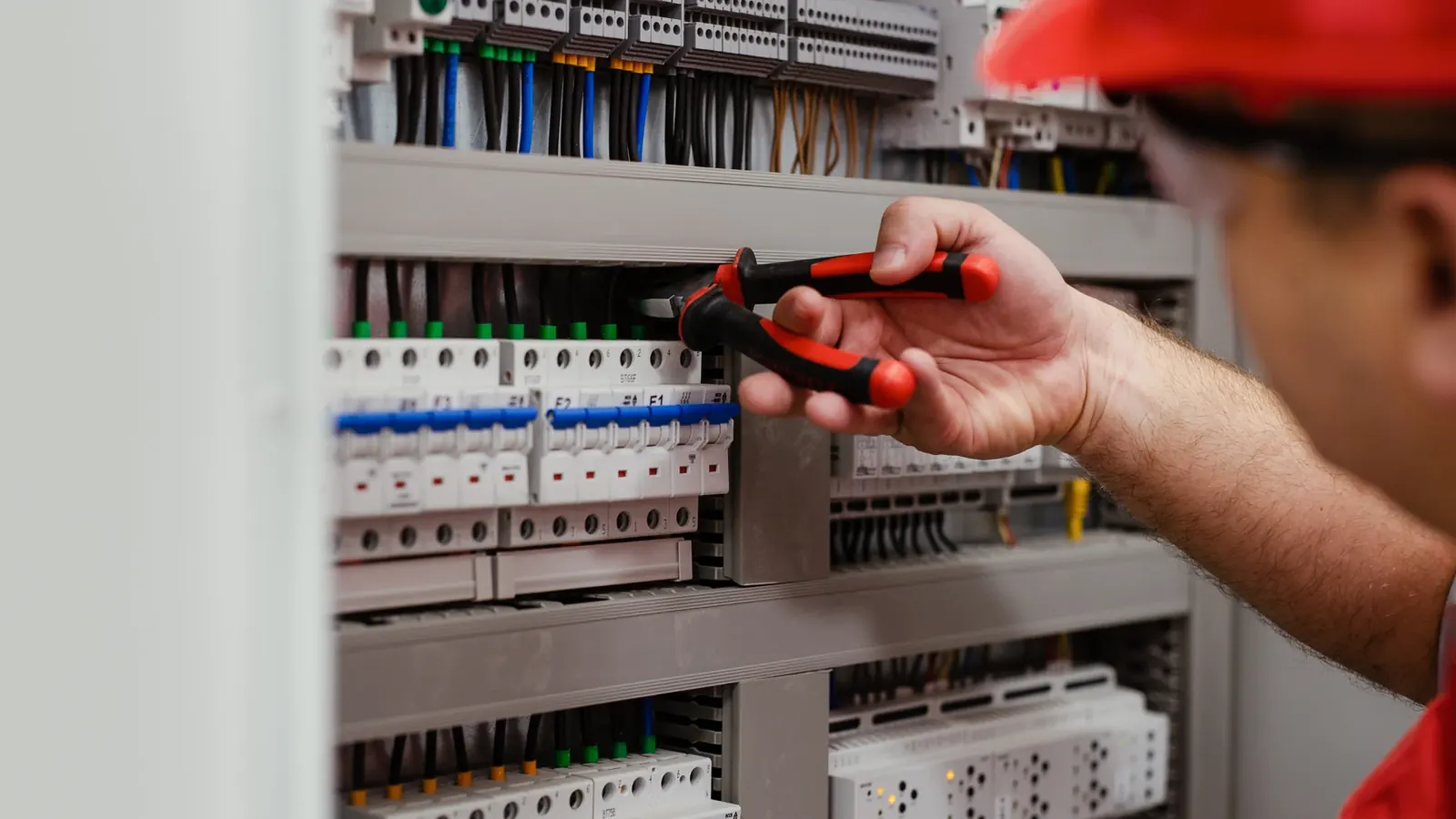 Eletricista a reparar um quadro elétrico com disjuntores